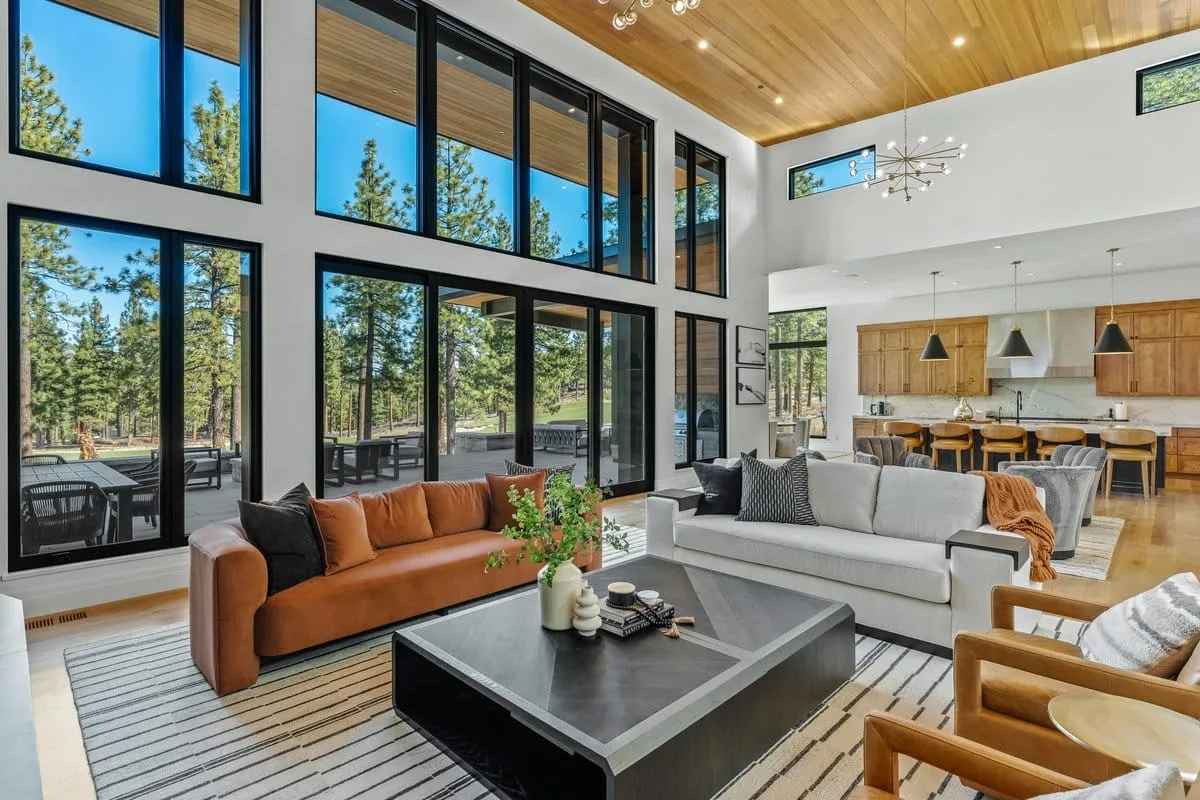 Living room with clerestory and floor-to-ceiling windows to the pines, a cedar ceiling and the kitchen island behind