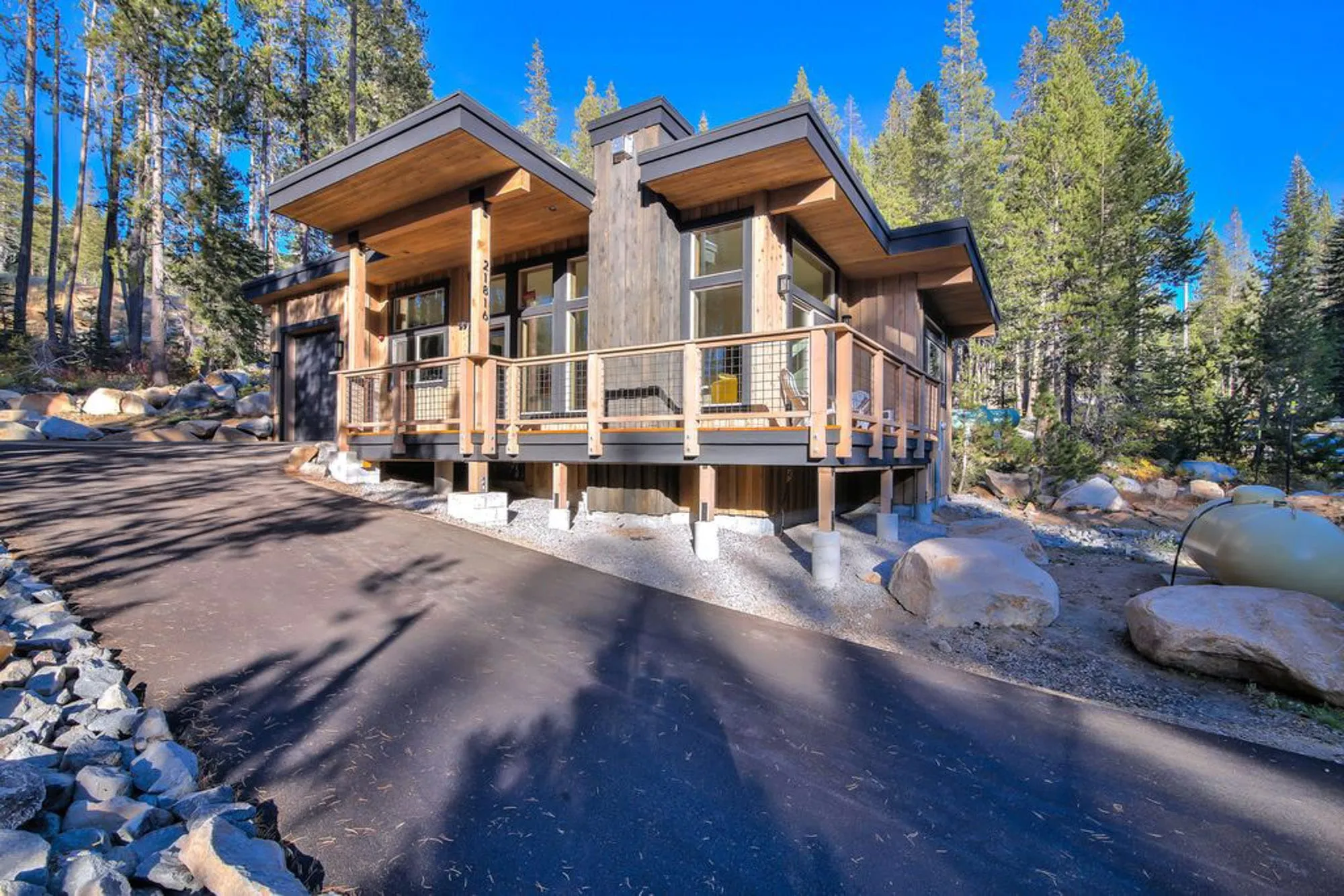 Tiny home with a shed roof and deep overhangs, wood siding and a raised porch with railing beside an asphalt driveway